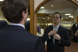 Customer looking into mirror while adjusting tie in a clothing store