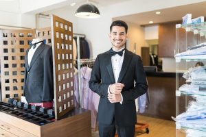 Person smiling while wearing tuxedo in rental store