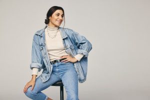 Person in denim jacket with jeans and necklace
